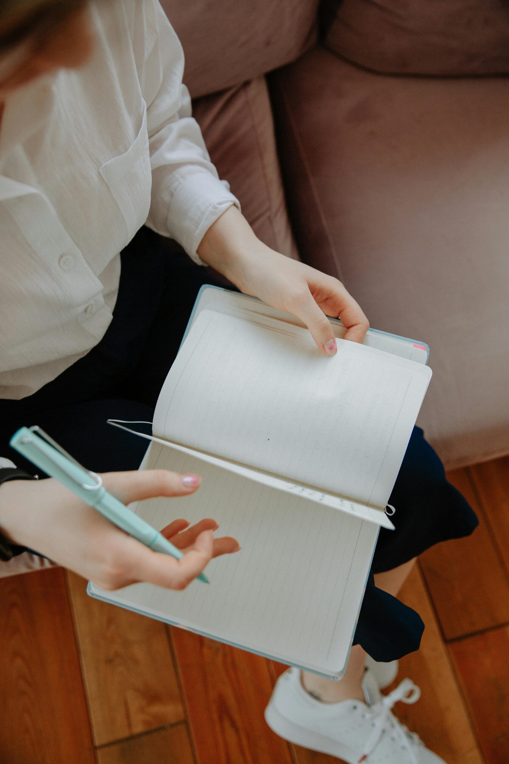 Overhead shot of an individual writing notes in a notebook, symbolizing a therapy or counseling session.